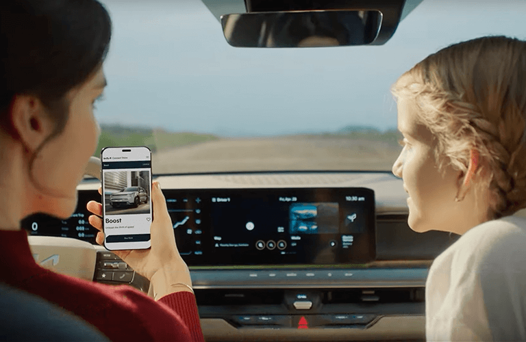 Two people in a vehicle holding a cellphone